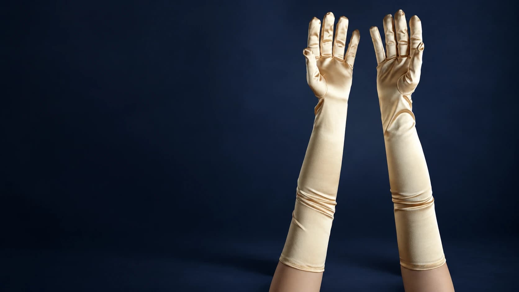 Ivory satin opera gloves photographed against a deep navy studio background